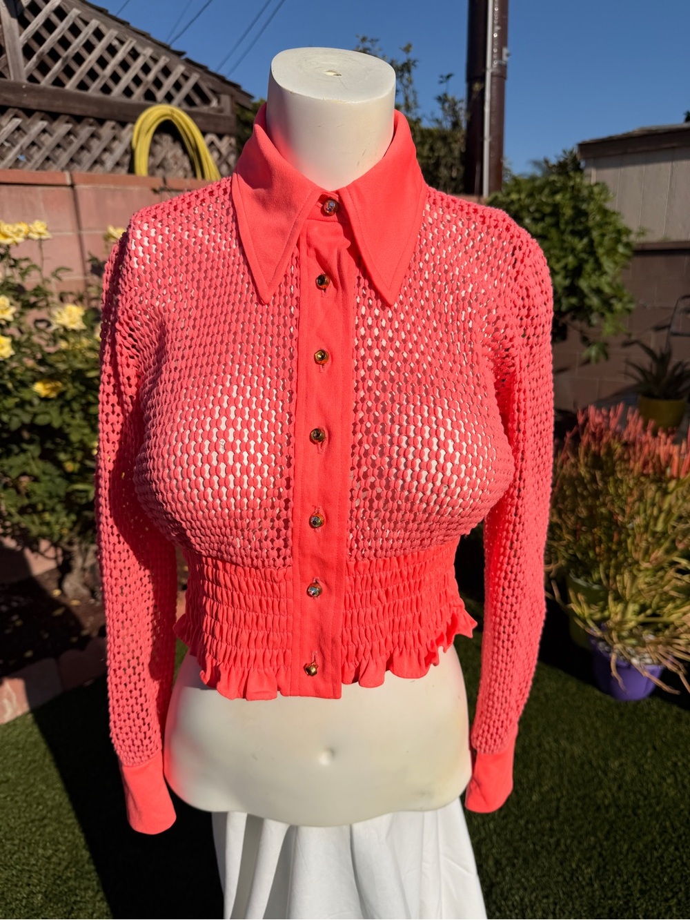 Hot pink fishnet-style cropped sweater jacket.